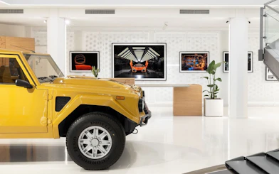 Yellow Lamborghini LM002 on display in a modern museum setting.