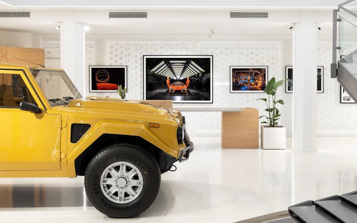 Yellow Lamborghini LM002 on display in a modern museum setting.