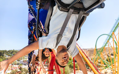 Riders enjoying WONDER WOMAN™ Flight of Courage roller coaster at Six Flags Magic Mountain.