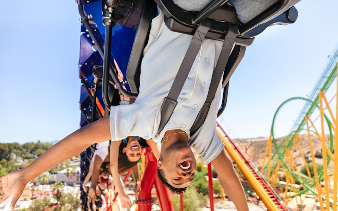 Riders enjoying WONDER WOMAN™ Flight of Courage roller coaster at Six Flags Magic Mountain.
