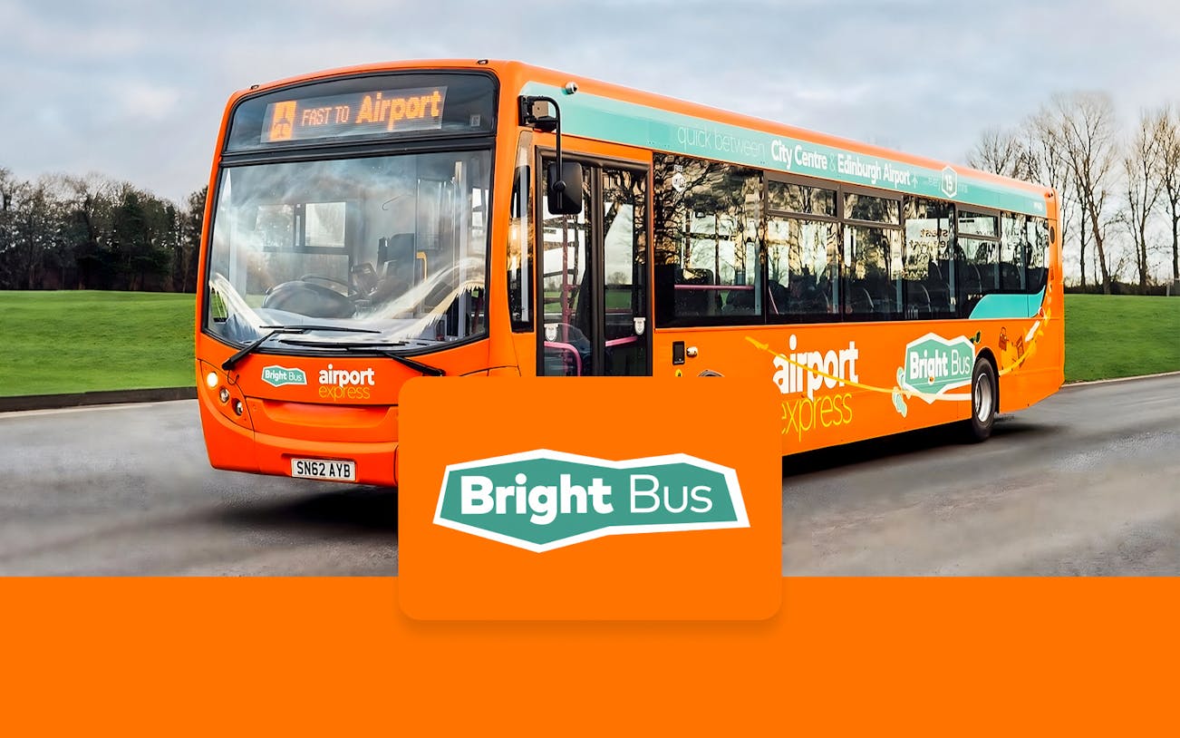 Bright orange airport express bus to Edinburgh Airport on a road.