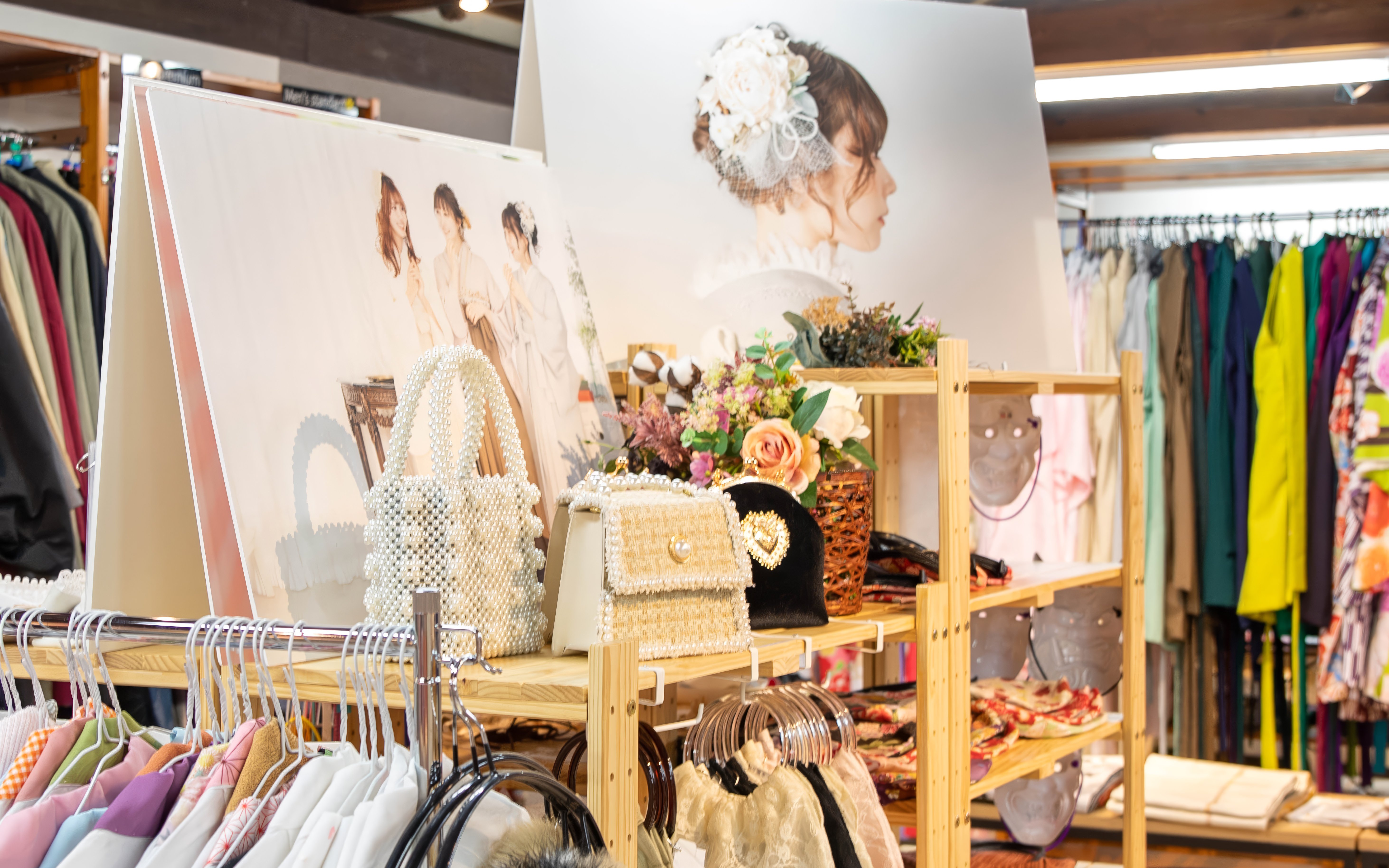 Kimono rental store interior with kimonos on racks, decorative bags, and floral displays.