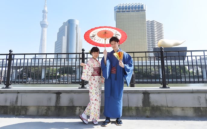 Couple in kimonos with umbrella at Asakusa, Tokyo Skytree in background.