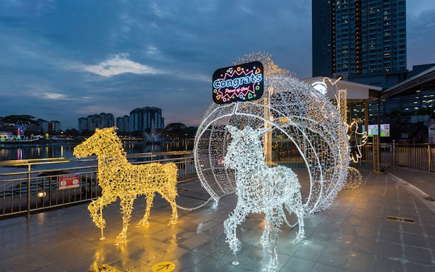 Illuminated horse sculptures at 99 Wonderland Park, Kuala Lumpur, with city skyline in the background.