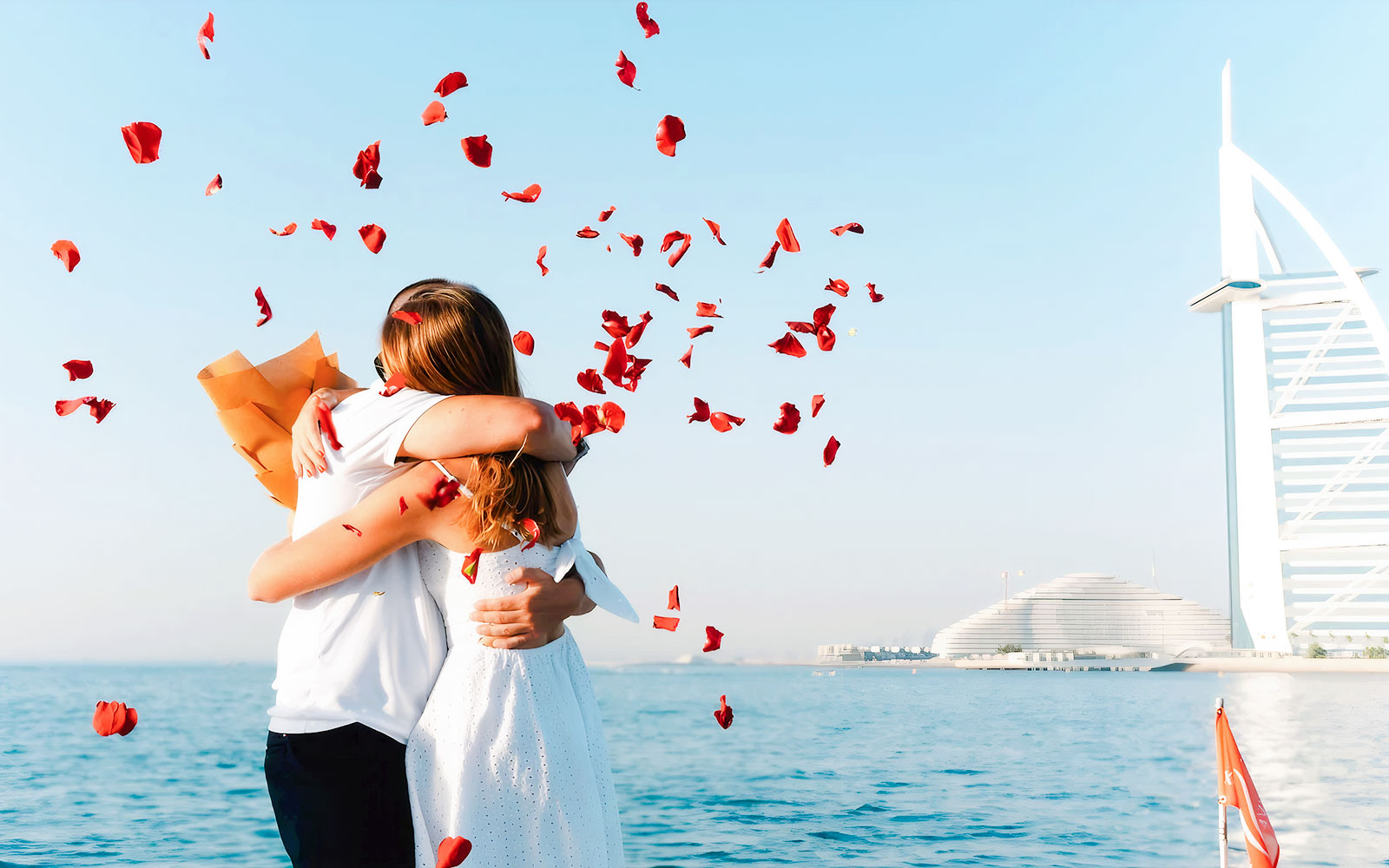 Couple embracing on a private yacht with Burj Al Arab in the background, Dubai.