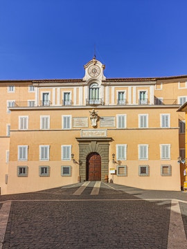 Facade of Castel Gandolfo with central clock and arched entrance, Italy.