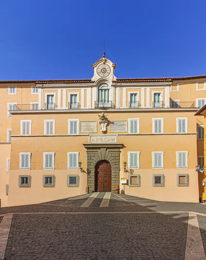 Facade of Castel Gandolfo with central clock and arched entrance, Italy.