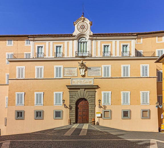 Facade of Castel Gandolfo with central clock and arched entrance, Italy.