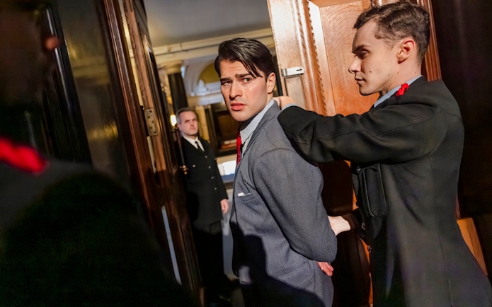 Cast members of "Witness for the Prosecution" in courtroom attire during a West End show scene.