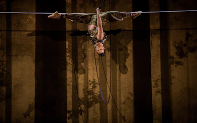 Performer suspended upside down during Cirque du Soleil Alizé stage show.