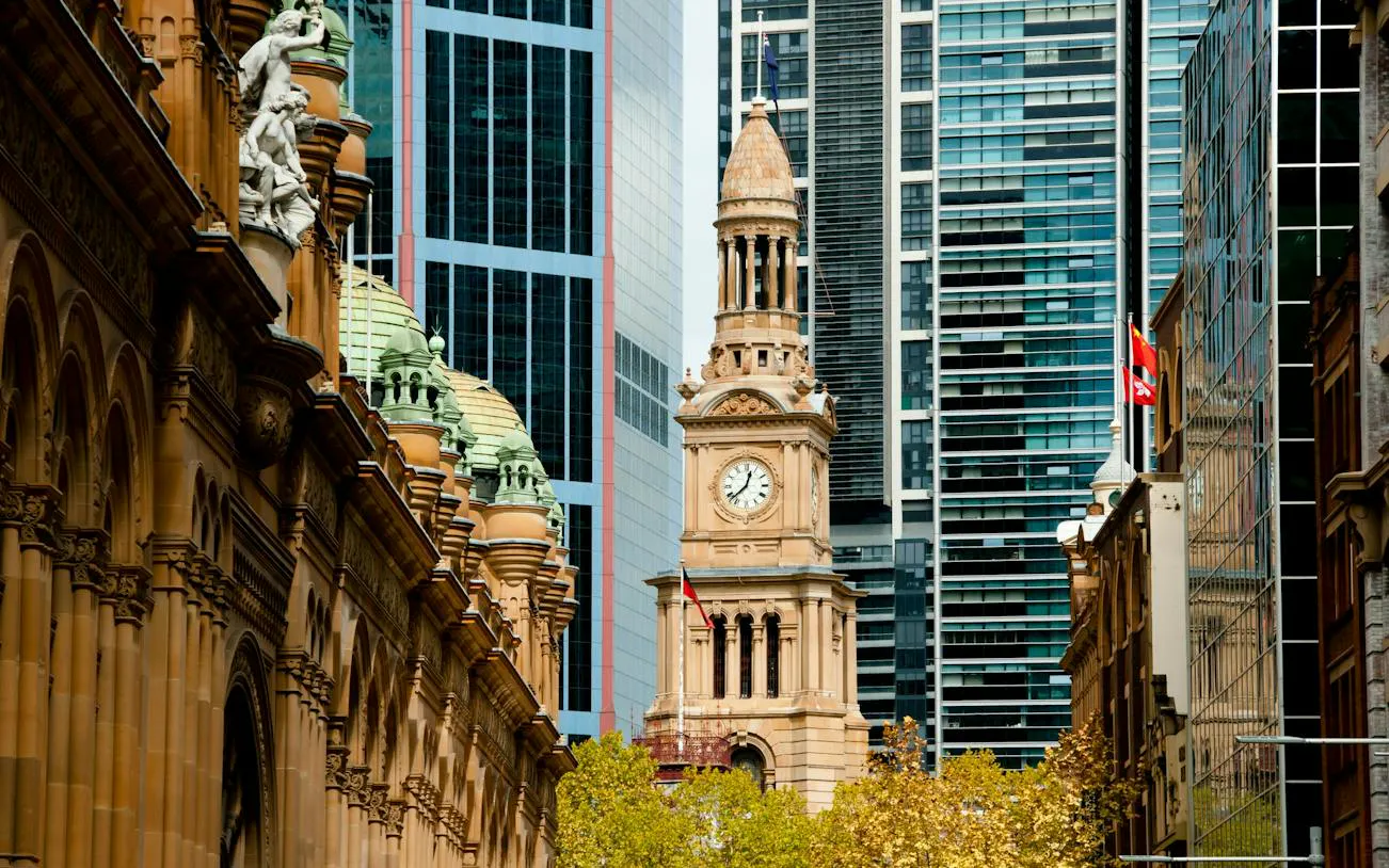 Clock tower and historic architecture of Sydney's Queen Victoria Building with modern skyscrapers in the background.