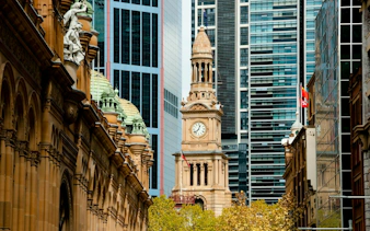Clock tower and historic architecture of Sydney's Queen Victoria Building with modern skyscrapers in the background.