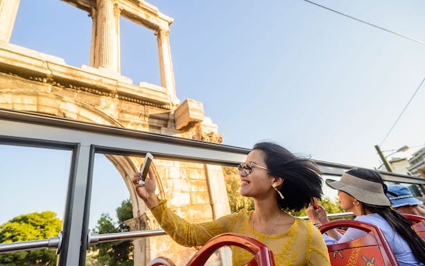 Woman taking a selfie on a City Sightseeing bus near Hadrian's Arch, Athens.