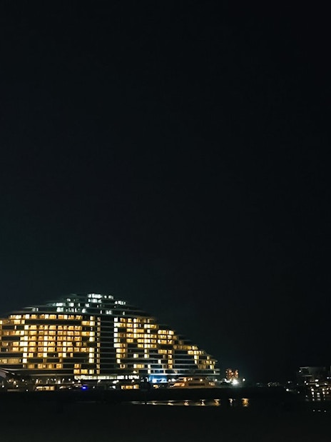 Palm Jumeirah beach at night with illuminated hotel and skyline.