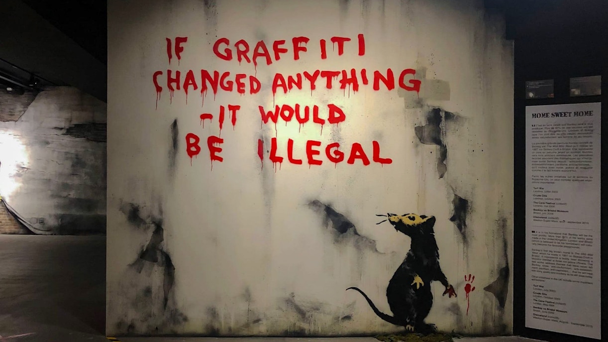 Graffiti art with a rat and text at Banksy Museum, Amsterdam.