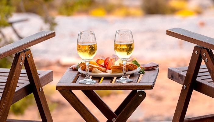 Breakfast setup with wine glasses and snacks on a wooden table in Ras Al Khaimah.