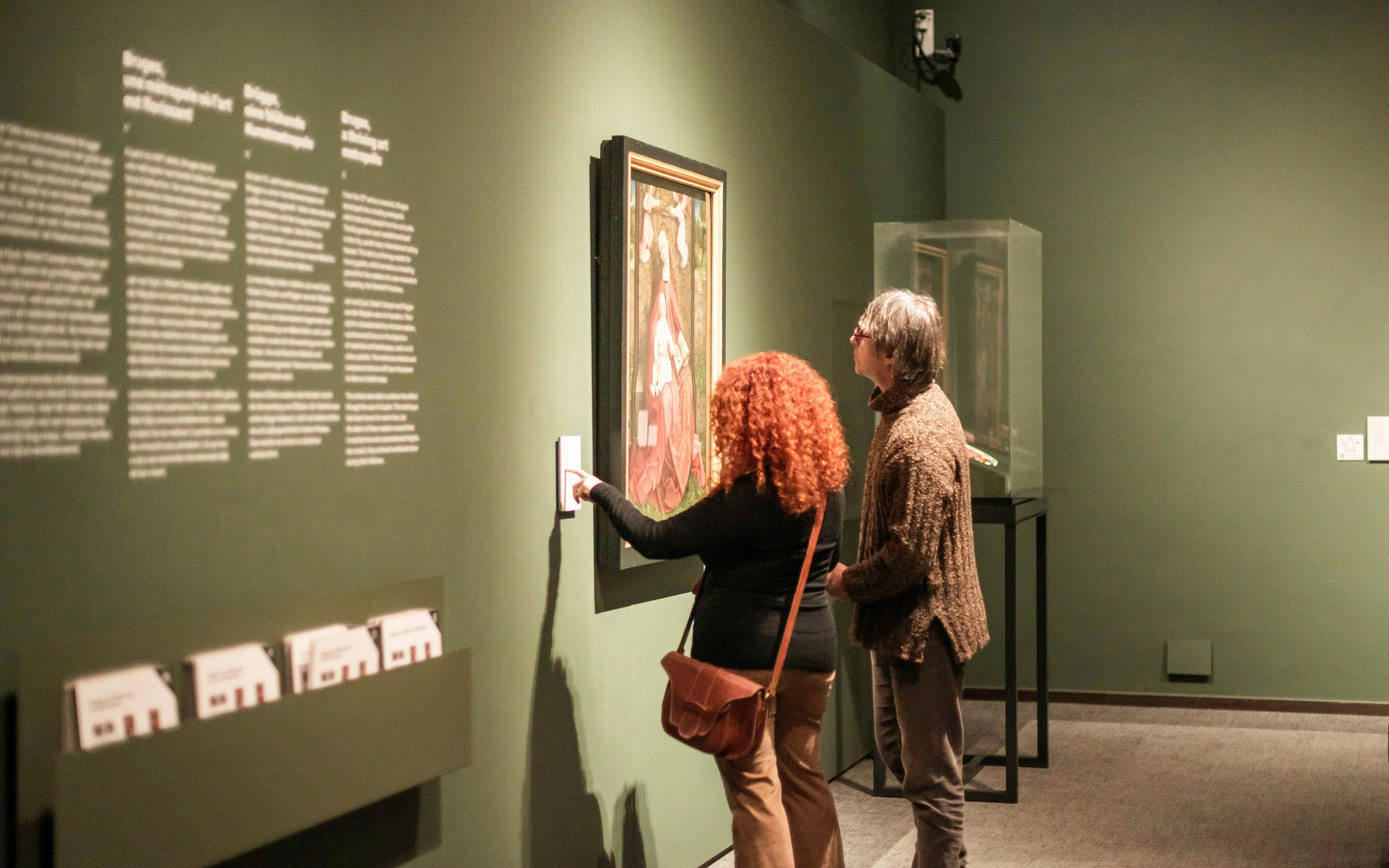 Visitors viewing artwork at Groeningemuseum exhibit.