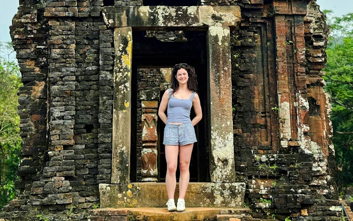 Tourist standing at ancient My Son Sanctuary entrance in Vietnam.
