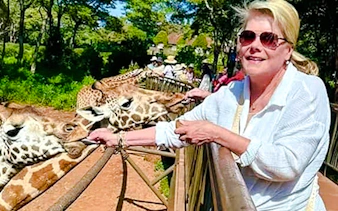 Visitor feeding giraffes at Nairobi Giraffe Centre during guided excursion.