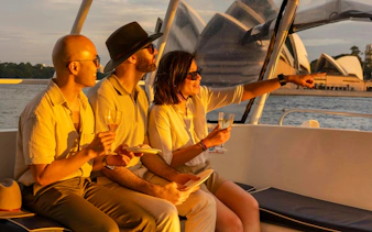 Guests enjoying Sydney Harbour Cruise at sunset with view of Opera House.