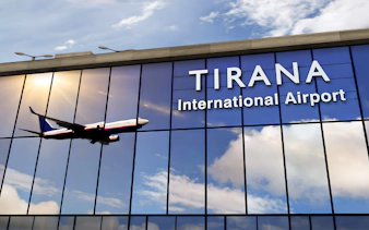 Tirana International Airport facade with airplane reflection.