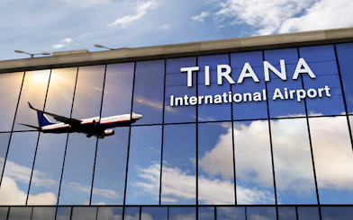 Tirana International Airport facade with airplane reflection.