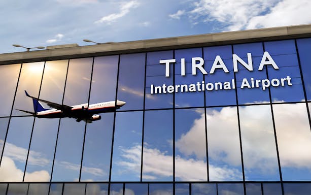 Tirana International Airport facade with airplane reflection.