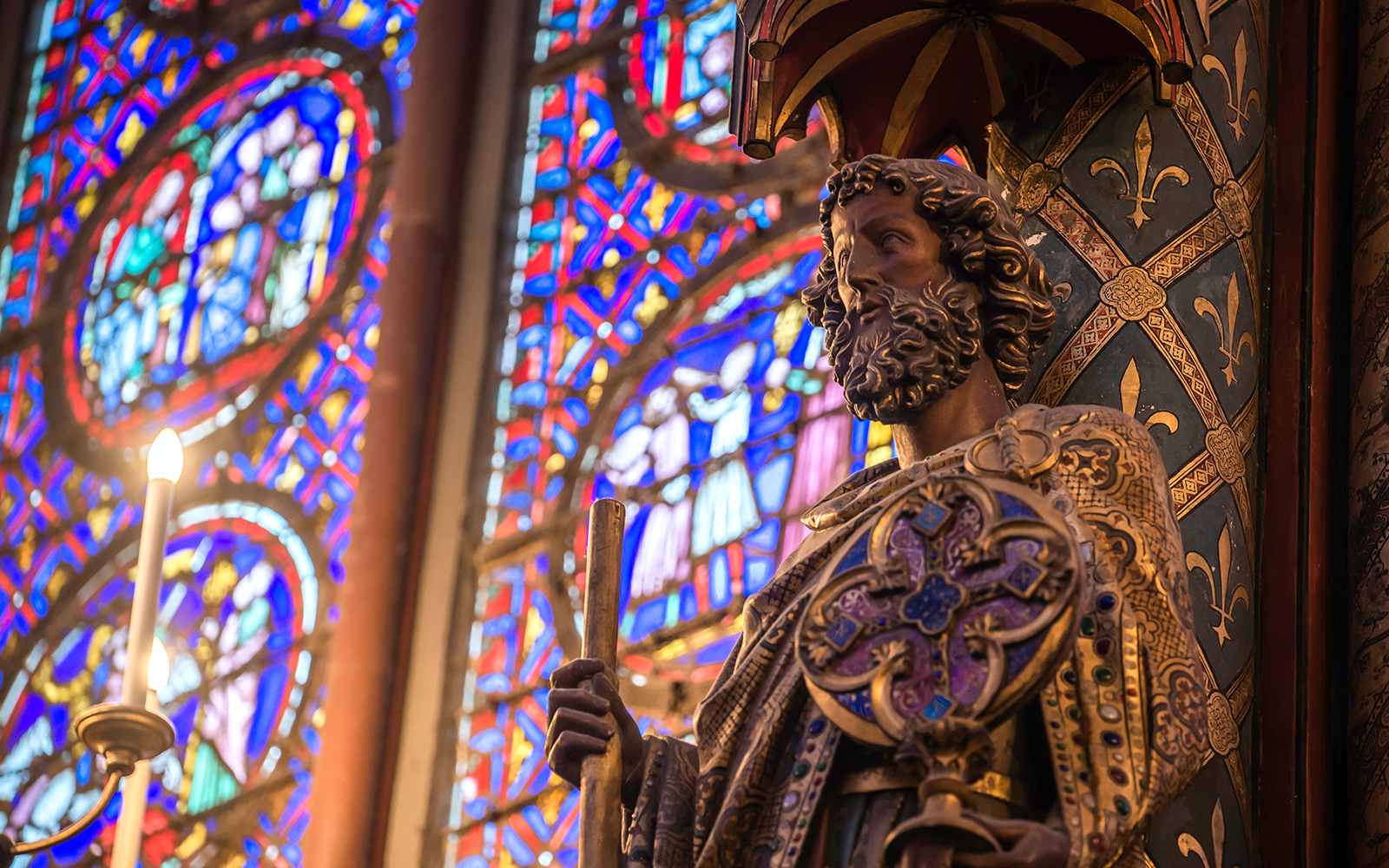 Stained glass and statue in Sainte-Chapelle, Paris, showcasing French monarchy's grandeur.