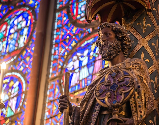 Stained glass and statue in Sainte-Chapelle, Paris, showcasing French monarchy's grandeur.