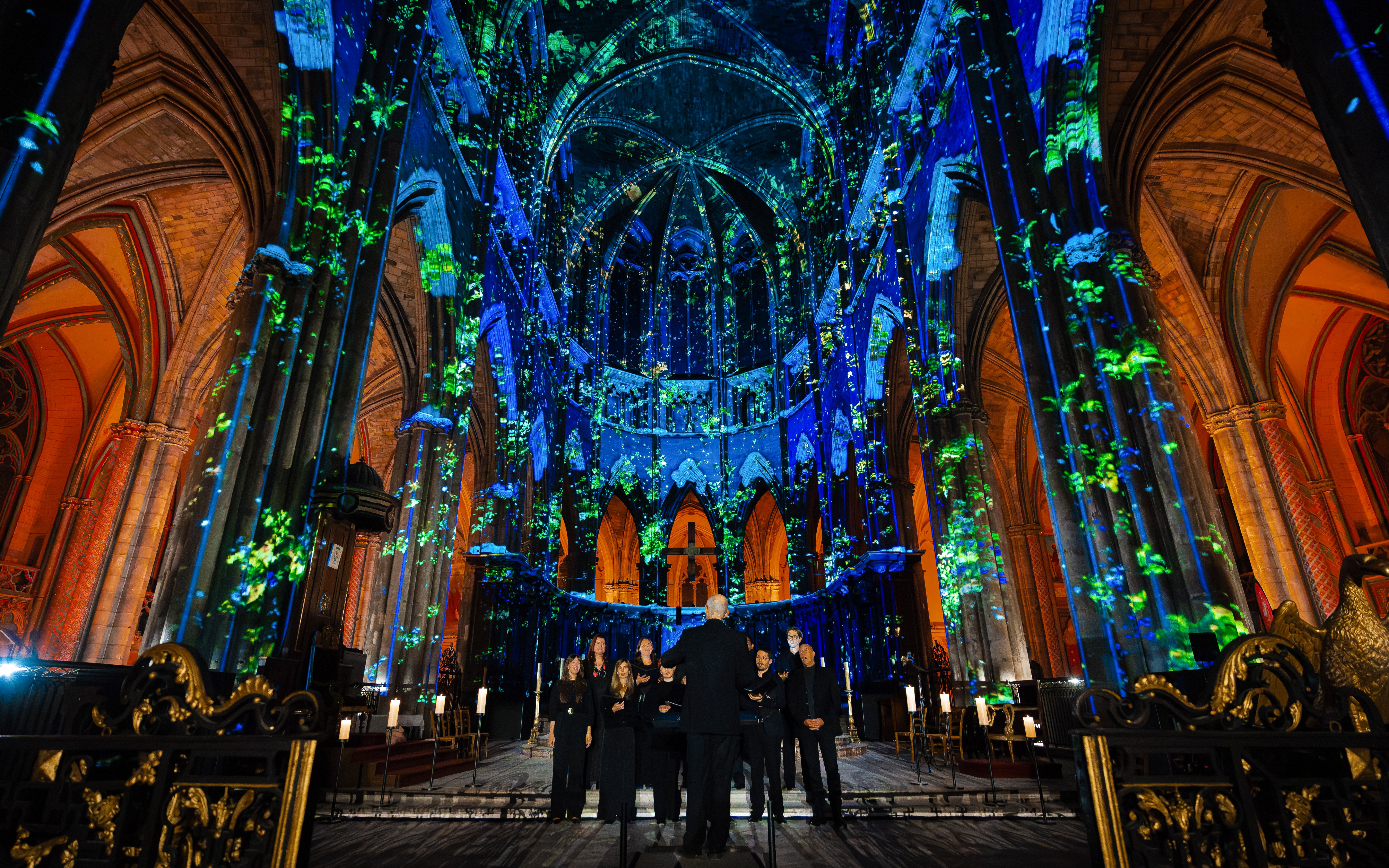 Manchester Cathedral interior during LUMINISCENCE 360° show with colorful light projections.