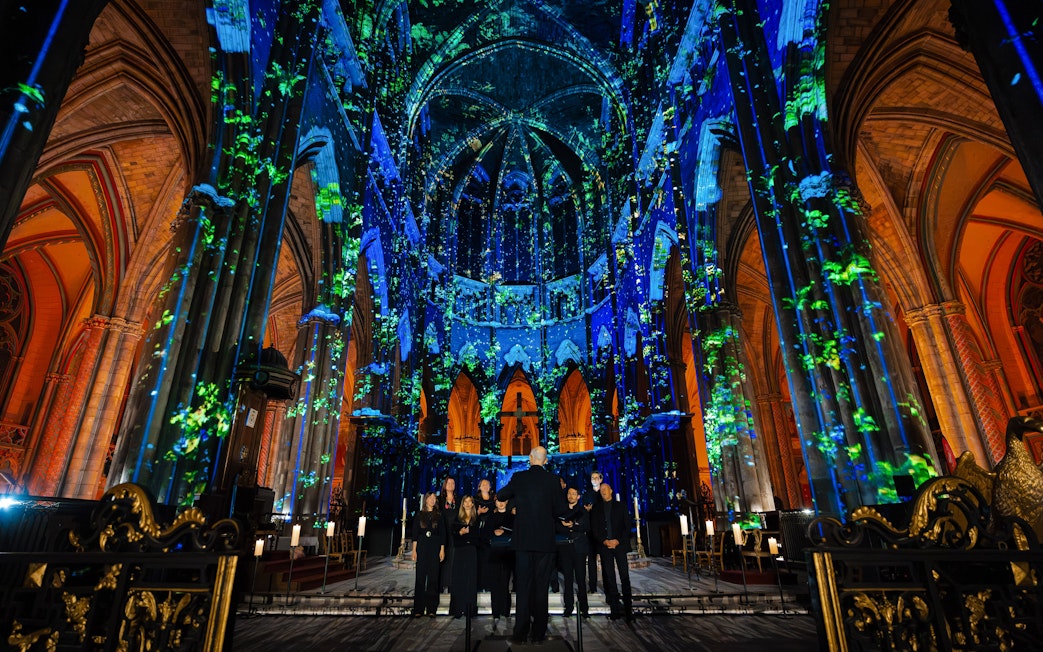 Manchester Cathedral interior during LUMINISCENCE 360° show with colorful light projections.
