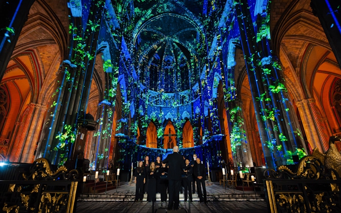 Manchester Cathedral interior during LUMINISCENCE 360° show with colorful light projections.