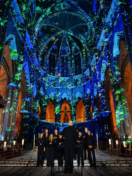 Manchester Cathedral interior during LUMINISCENCE 360° show with colorful light projections.