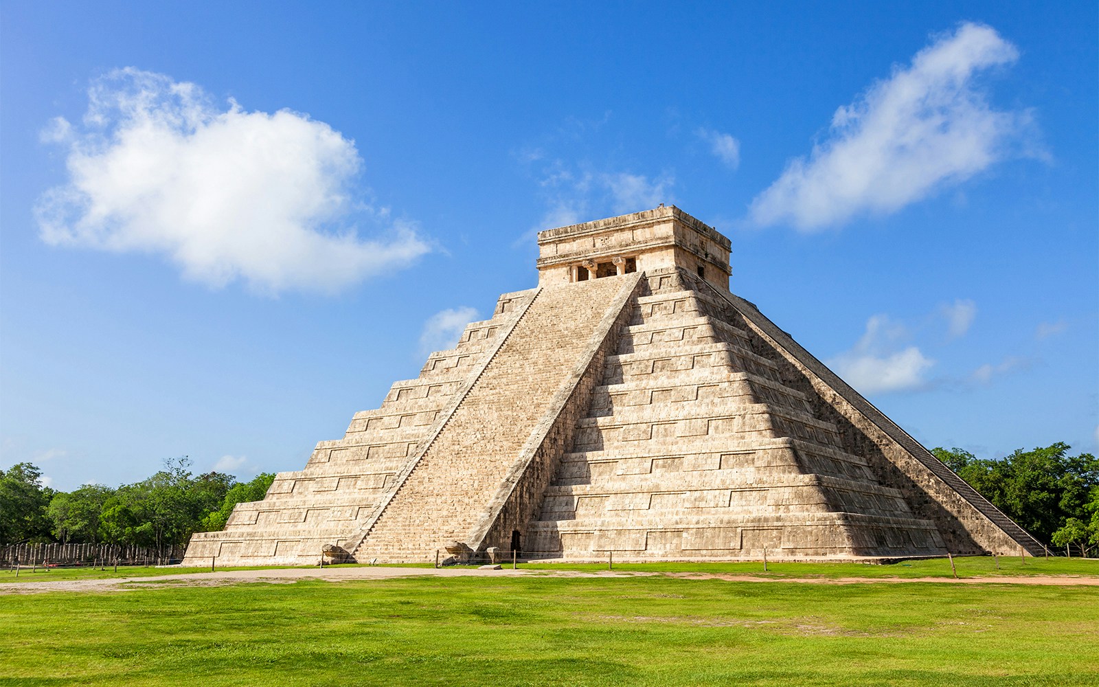 Chichén Itzá pyramid in Cancún, Mexico, with tourists exploring the ancient Mayan site.