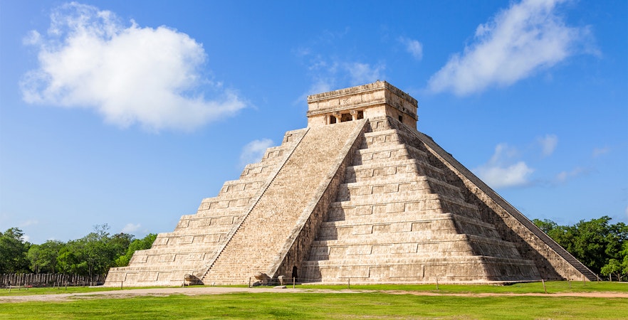 Chichén Itzá pyramid in Cancún, Mexico, with tourists exploring the ancient Mayan site.