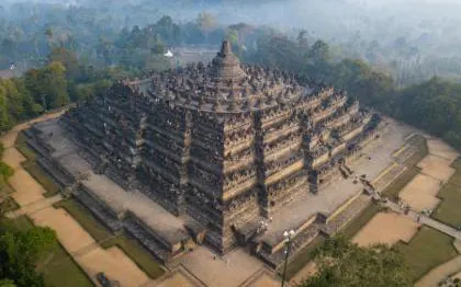 Borobudur Temple aerial view, ancient stone structure surrounded by lush greenery, Java, Indonesia.