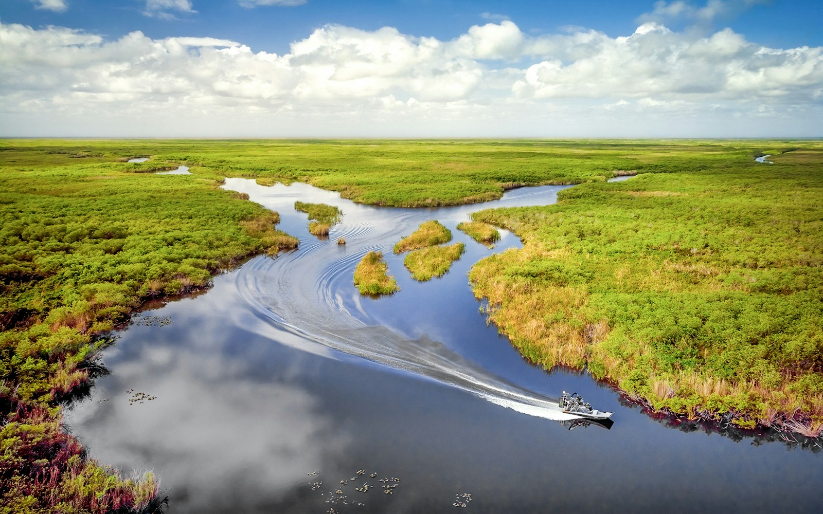 Aerial view of Everglades with airboat navigating through winding waterways.