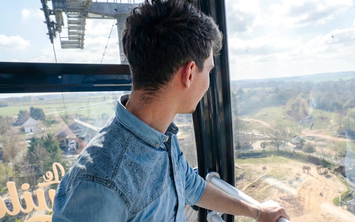 Man observing Zooparc de Beauval landscape from cable car, Loire Valley, France.