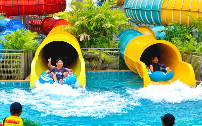 People exiting colorful water slides at SplashMania Waterpark.