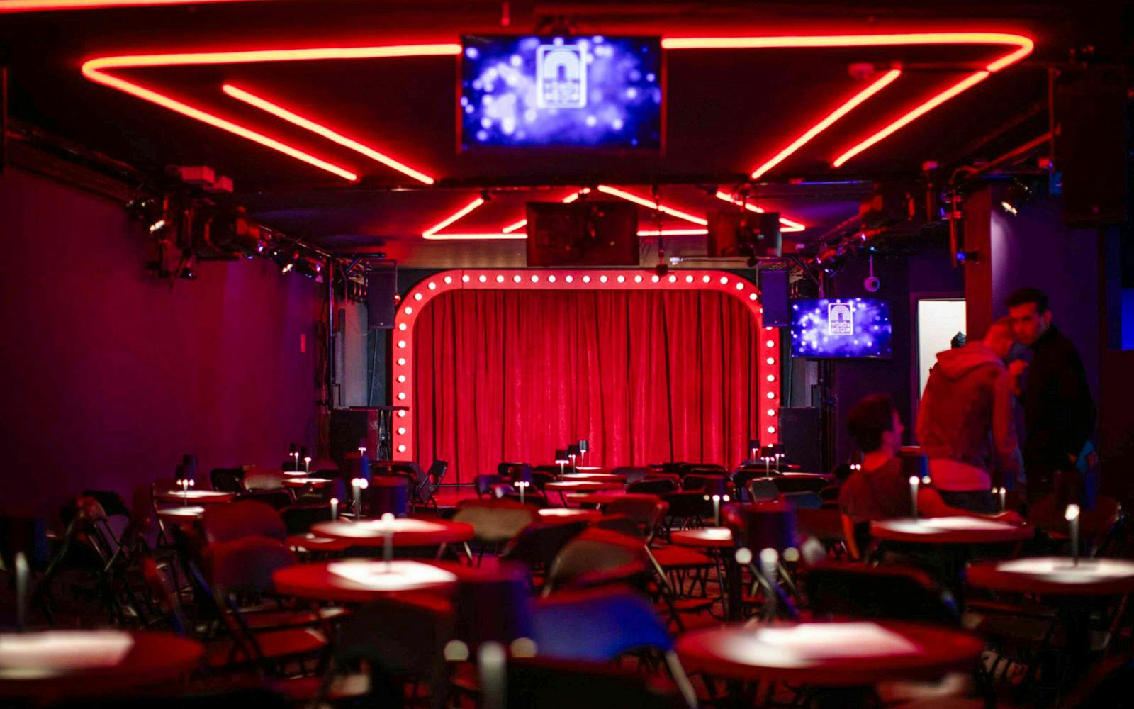 Venue setup with red curtains and neon lights for Drag Queen Hungary Show.