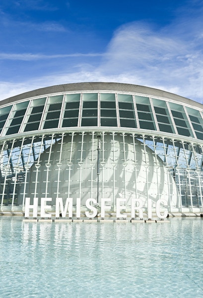 Hemisferic building with glass facade reflecting in water, Valencia, Spain.