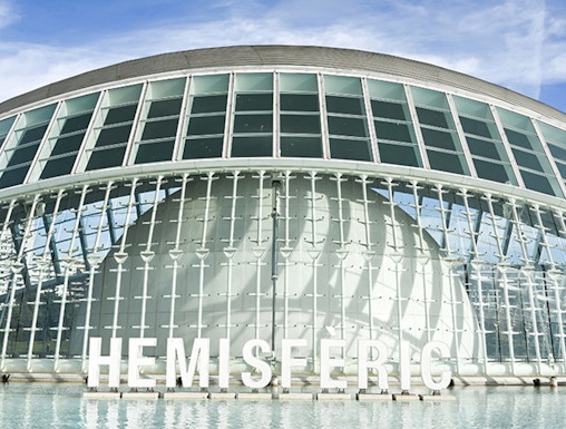 Hemisferic building with glass facade reflecting in water, Valencia, Spain.