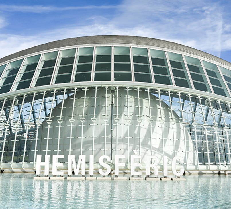 Hemisferic building in Valencia, Spain, reflecting in water at sunset.