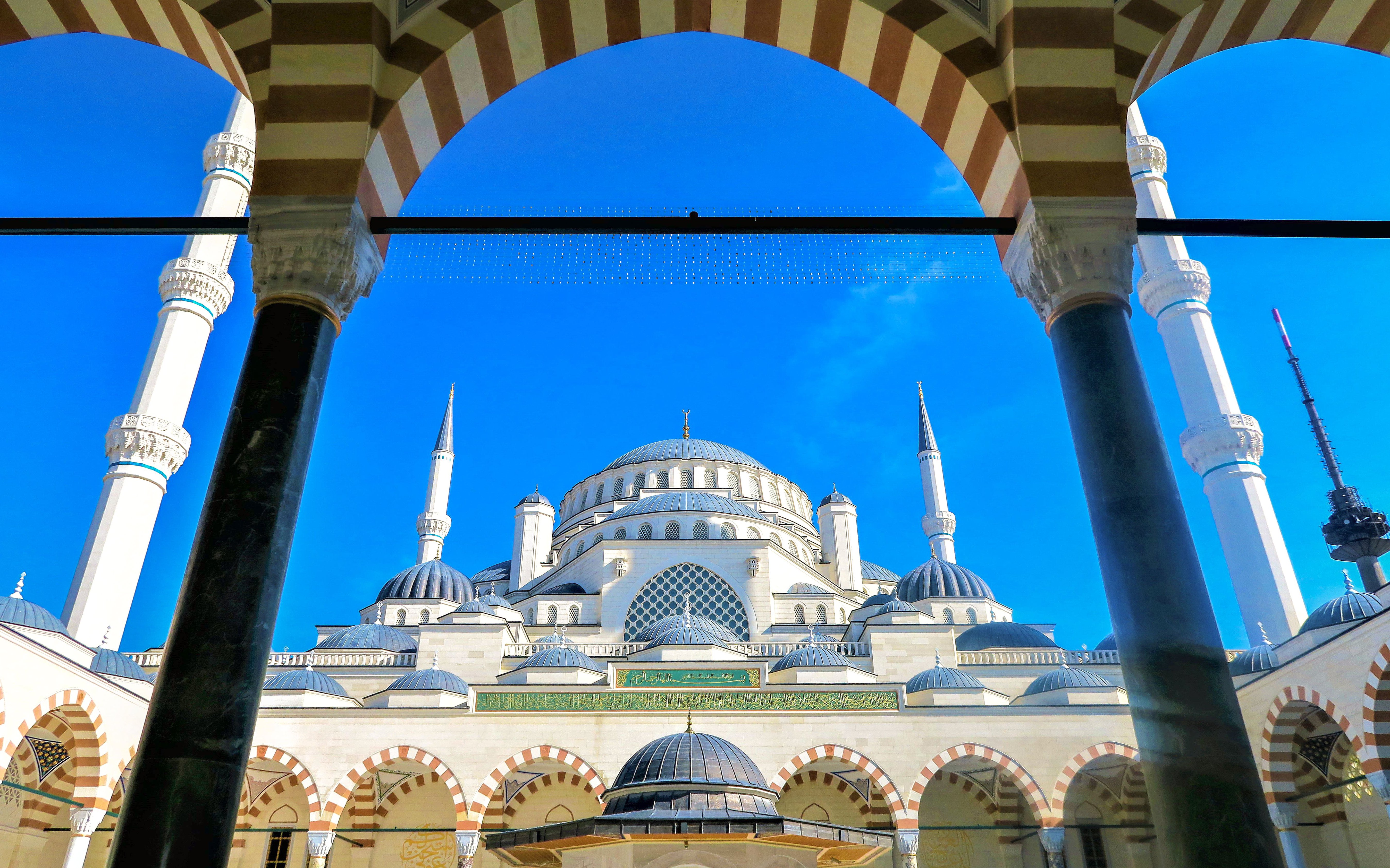 Blue Mosque in Istanbul framed by arches and minarets against a clear blue sky.