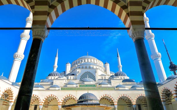 Blue Mosque in Istanbul framed by arches and minarets against a clear blue sky.