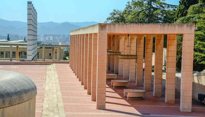 Montjuic Olympic Ring colonnade with cityscape and mountains in the background, Barcelona.