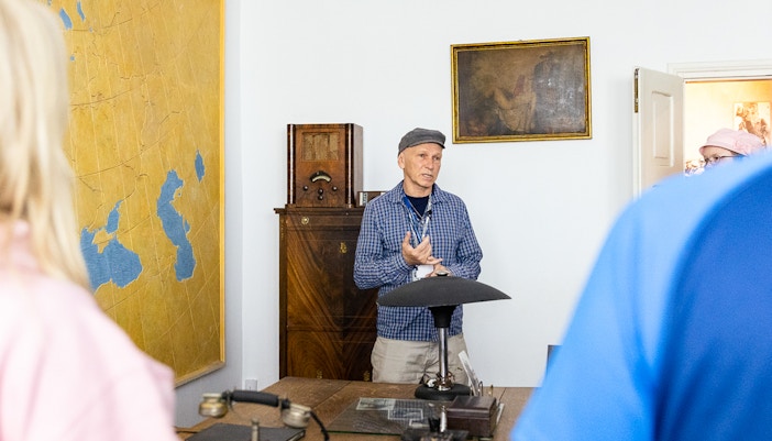 Tour guide explaining historical artifacts at Oskar Schindler's desk in Schindler's Factory, Krakow.