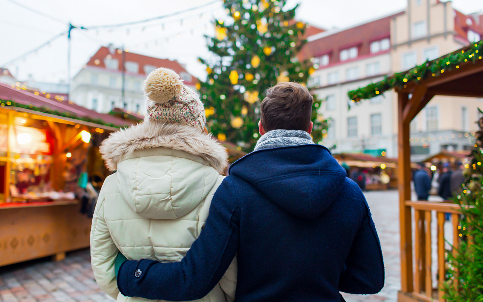 Couple exploring a festive Christmas market in a European city.