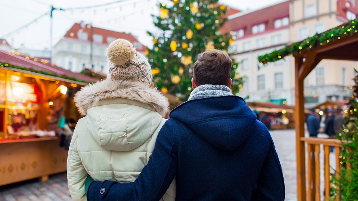 Couple exploring a festive Christmas market in a European city.