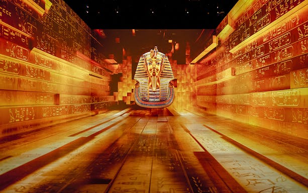 Tutankhamun mask projection in immersive exhibition with hieroglyphic walls.